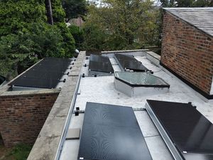 Multiple solar panel arrays on flat roof with skylight in Rushholme