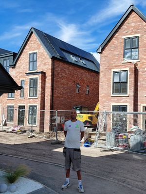 Installer at new build development with solar panels on roofs