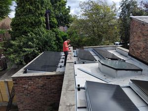 Solar panel installation in progress on flat roof in Rusholme