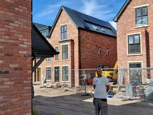 Installer with completed solar panel installation on new build houses